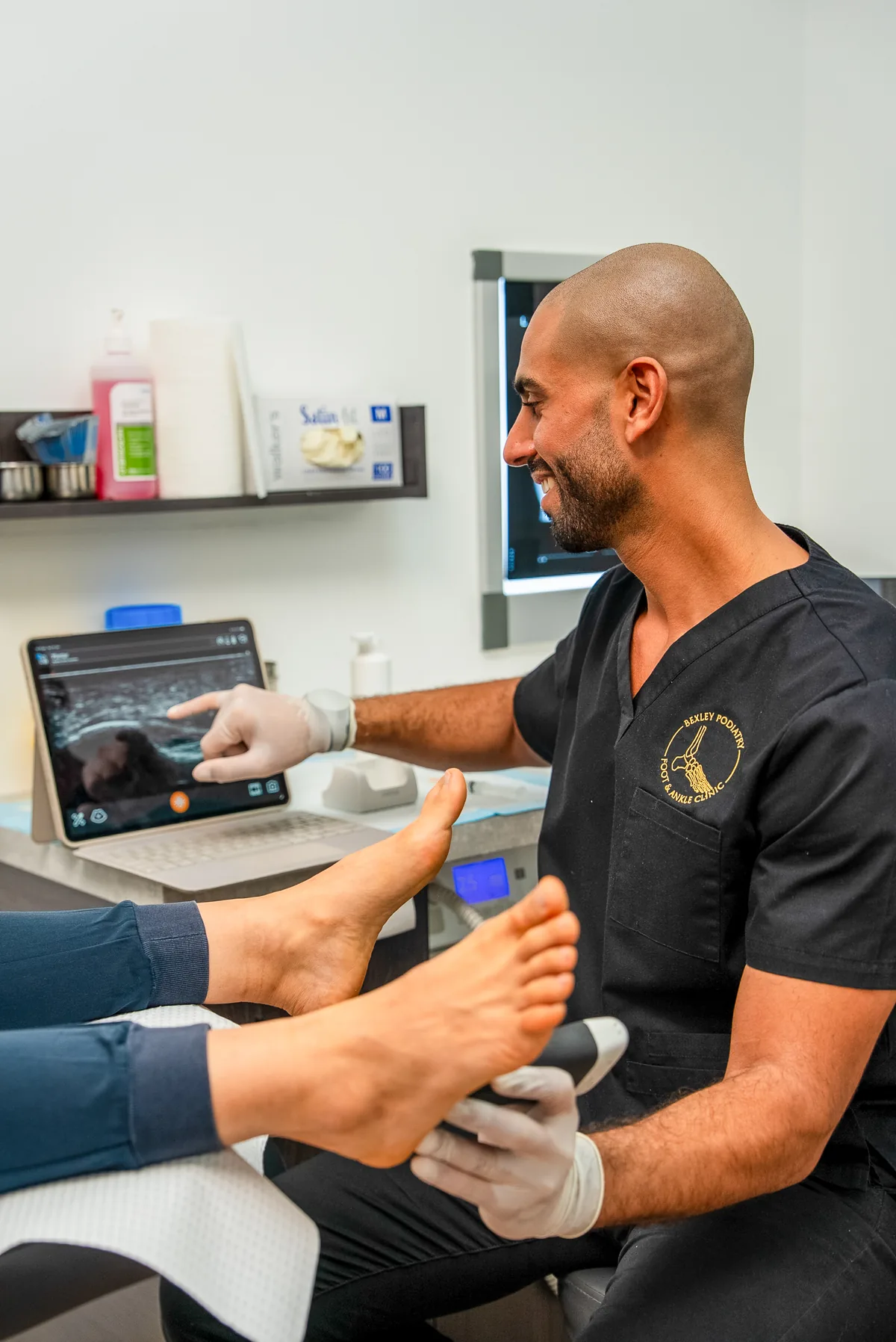A podiatrist delivering shockwave therapy to a patient's foot at the Bexley clinic